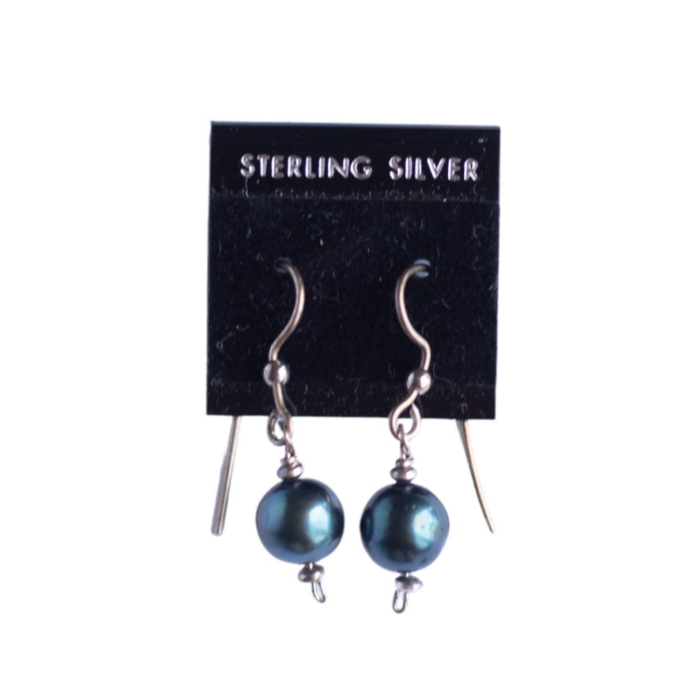 The photo shows a pair of sterling wire earrings with blue-black dyed fresh water cultured pearls hanging on a black earring card.