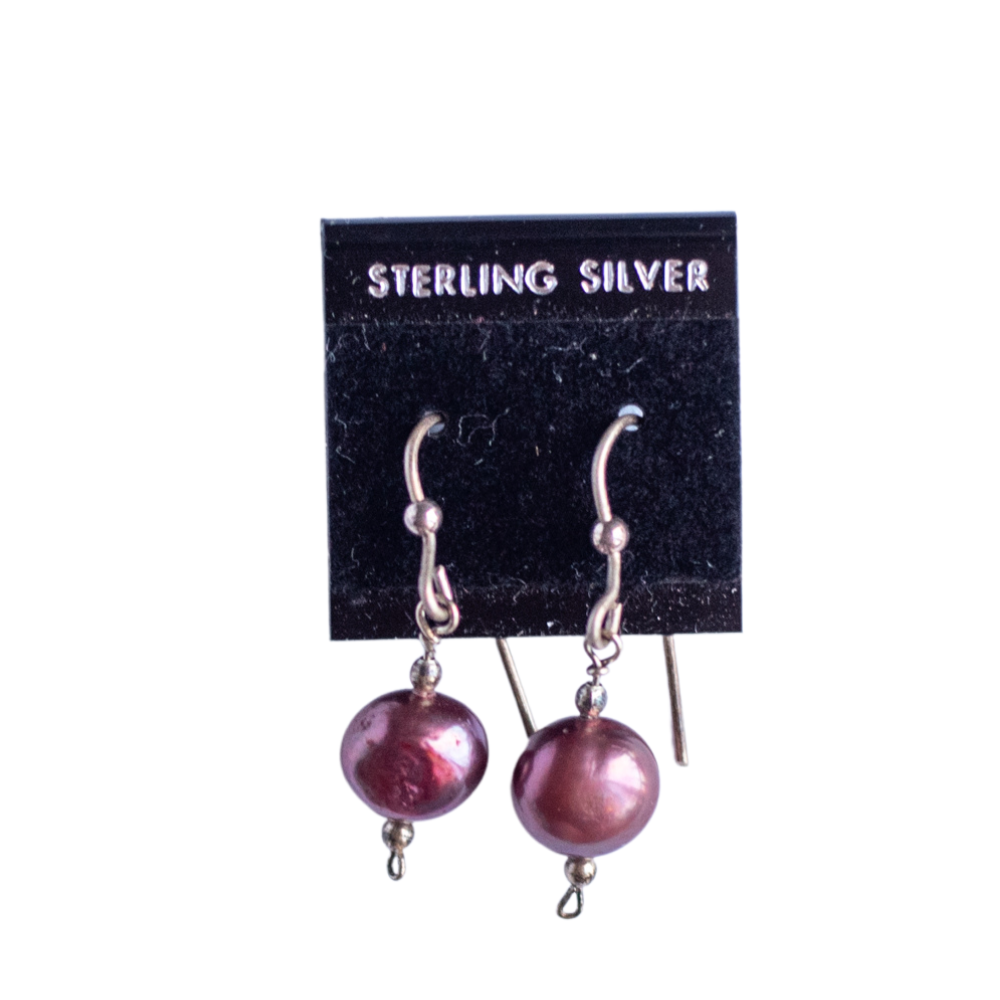 The photo shows a pair of fresh water cultured pearl earrings on a black earring card the pearls are dyed a burgundy . The wirework is sterling silver.