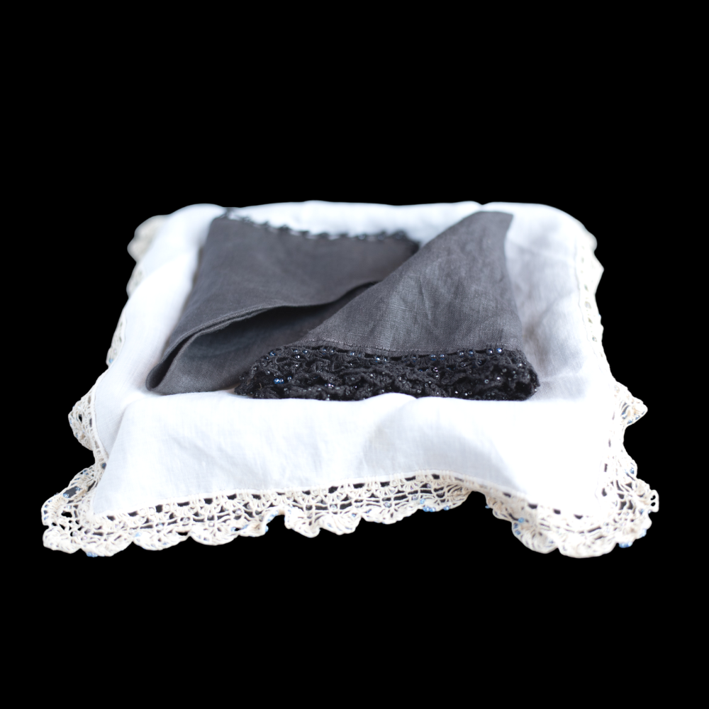The photo shows black linen hand laced handkerchiefs, on top of white linen hand laced handkerchiefs.