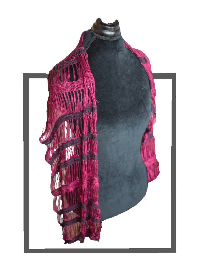The photo shows an image of a bright burgundy Blue moon Fiber Arts Silk Thread II and Art Yarns black cherry silk essence dark red silk wrap in broomstick lace arranged on a mannequin. with a gray gingham background.