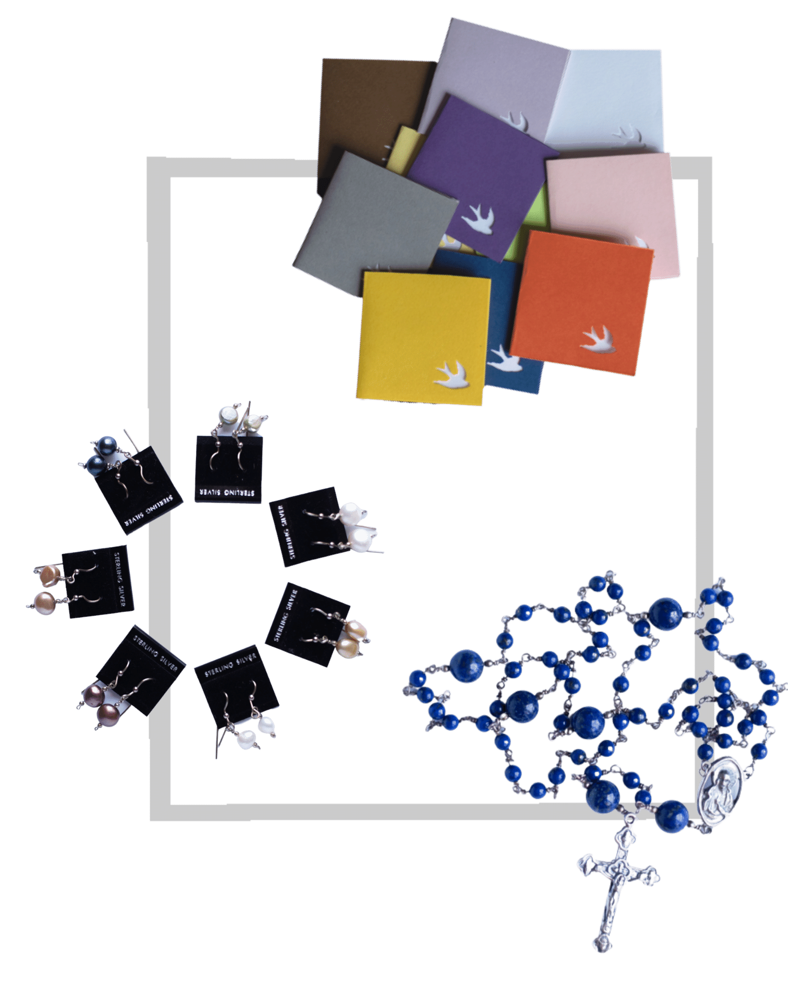 Photo shows several 2 inch by 2 inch notecards with a bird punch in the corner, a ring of seven pairs of freshwater pearl earrings, and a lapis rosary arranged on a gray gingham background.