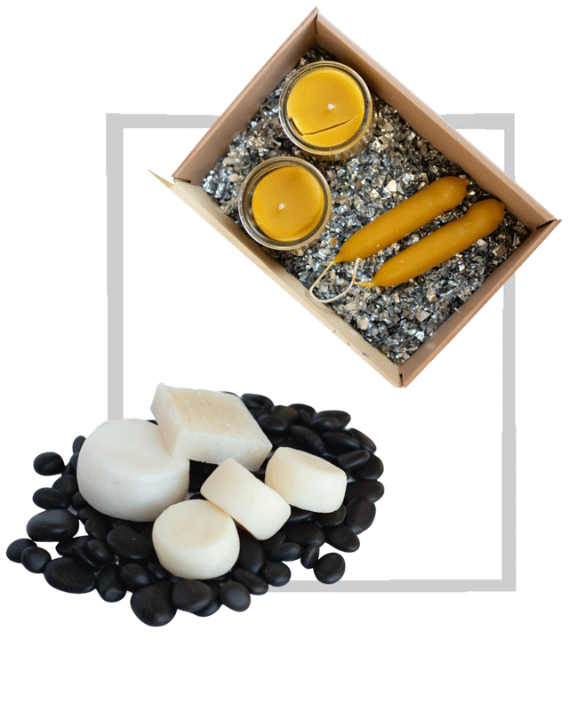 The photo shows four candles arranged in a cardboard box with decorative glitter and five bars of soap arranged on decorative black stones.
